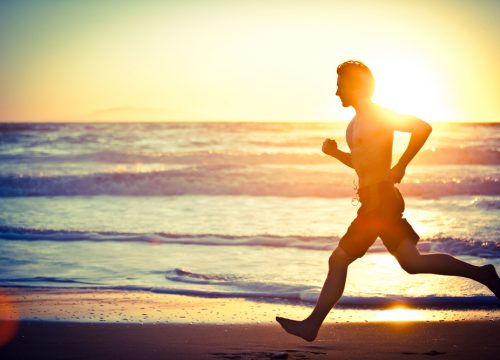 Photo of a man running on the beach at sunset