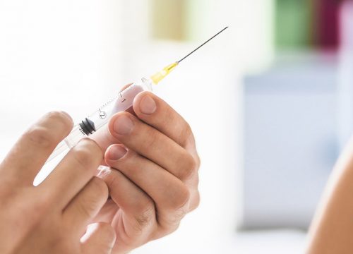 Photo of a nurse giving a patient a shot in the shoulder