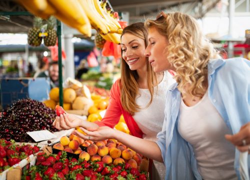 Young happy healthy women shopping vegetables and fruits on the market